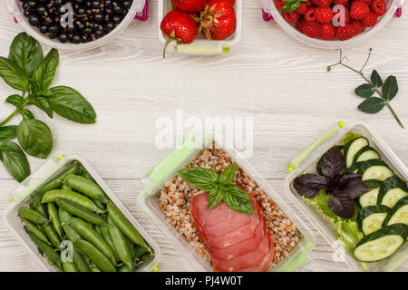 Kunststoff Mahlzeit prep Container grüne Erbsen, mit gekochten Buchweizen Brei und Scheiben von Fleisch, frischen Gurken und Salat, Johannisbeere, Erdbeere, Himbeere, Stockfoto