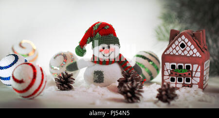 Spielzeug Schneemann und ein Lebkuchenhaus auf einem hellen Hintergrund. Stockfoto