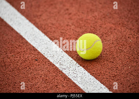 Tennisplatz: gelbe Kugel und weiße Linie auf einer ockerfarbenen Hintergrund, ähnlich Ton Stockfoto