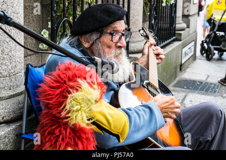 Eine ausgereifte busker Gitarre spielen und singen in einer Straße in Truro Cornwall. Stockfoto