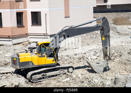 Einem großen eisernen Baggerschaufel sammelt und schüttet Sand Geröll und Steinen in einem Steinbruch auf der Baustelle Straße Einrichtungen und Häuser Stockfoto