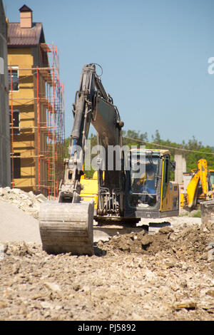 Einem großen eisernen Baggerschaufel sammelt und schüttet Sand Geröll und Steinen in einem Steinbruch auf der Baustelle Straße Einrichtungen und Häuser Stockfoto