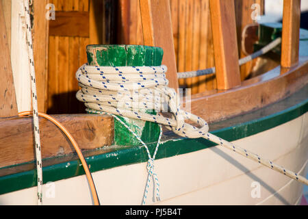 Detail eines hölzernen Segelboot, und ein Seil um einen bitt für die Befestigung am Ufer Stockfoto