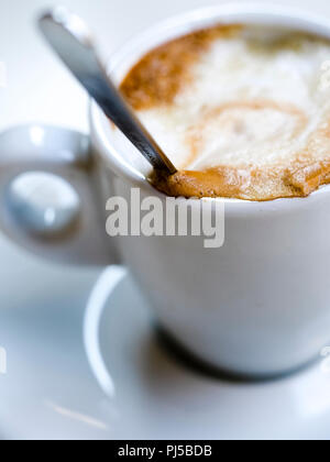 Nahaufnahme Makroaufnahme eines klassischen macchiato Espresso Kaffee in einer Bar aus weißem Porzellan Schale auf weißem Hintergrund mit Löffel - Stockfoto