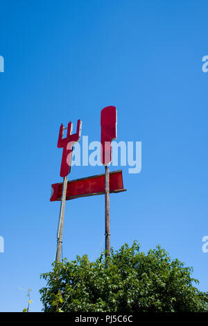 Niedrigen winkel Foto Blick auf eine alte Plattenausschnitt der großen roten Messer und Gabel Werbung ein Restaurant senkrecht nach oben kleben vor blauem Himmel Stockfoto