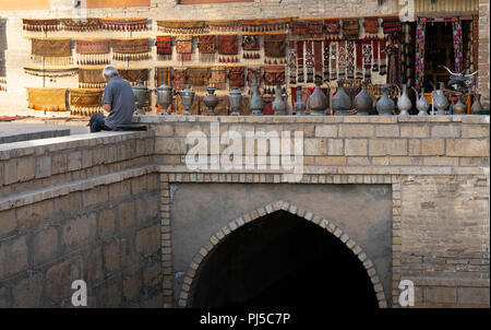 Alter Mann in einem Markt Straße in Buchara Usbekistan mit Teppich und Vasen Stockfoto