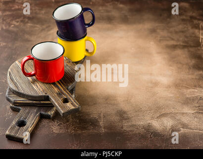 Bunte Keramik Becher mit Emaille Blick auf hölzernen cutboard Stockfoto