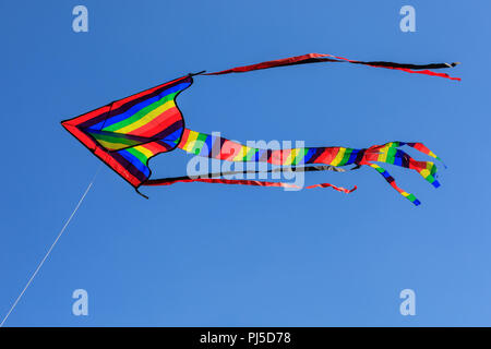 Rainbow farbige Drachen gegen den tiefblauen Himmel fliegen Stockfoto