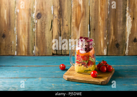 Gesunde hausgemachte Mason Jar-Salat mit Kichererbsen, Mais, Karotten, Gurken, Paprika, Radieschen, Rucola und Spinat - gesunde Ernährung, Diät oder Detox, Veg Stockfoto