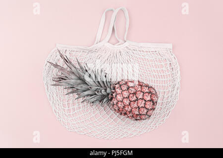 Farbenfrohe Sommer Shopping-legen. Reife Ananas über Baumwolle Mesh bag, Ansicht von oben, kopieren. Sommer Shopping verkauf Routine und Urlaub, Pastellfarben, Stockfoto