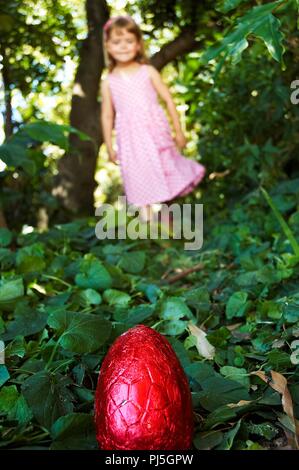 Ein kleines Mädchen auf der Jagd nach Schokolade Ostereier. Stockfoto