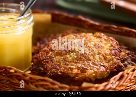 Frische, hausgemachte Reibekuchen oder dünne Pfannkuchen in Korb mit Apfelmus auf der Seite, einem traditionellen deutschen Snack oder Gericht namens Kartoffelpuffer Stockfoto