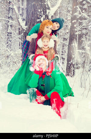 Familie in der traditionellen Weihnachtsstern Kostüme, rot-grüne, Helfer Elfen Santa's, im Winter Wald mit einer Truhe von Geschenken und einem riesigen Candy Stockfoto