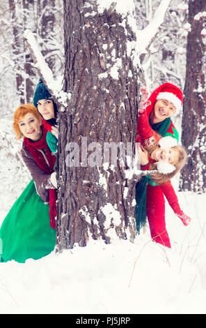 Familie in der traditionellen Weihnachtsstern Kostüme, Rot-Grün, Santa's Helfer - die Elfen, im Winter Wald mit einer Truhe von Geschenken und einem riesigen Candy Stockfoto