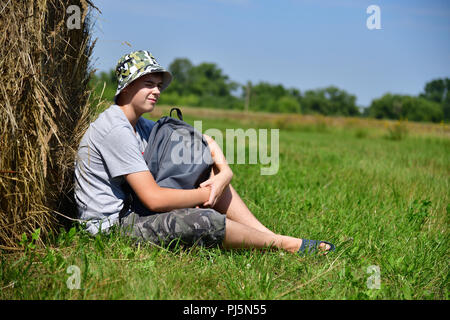 Teenager mit einem Rucksack saß ein Stroh Stapel Stockfoto