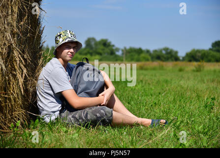 Teenager mit einem Rucksack saß ein Stroh Stapel Stockfoto