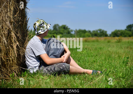 Teenager mit einem Rucksack saß ein Stroh Stapel Stockfoto