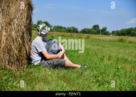 Teenager mit einem Rucksack saß ein Stroh Stapel Stockfoto