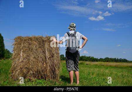 Jugendlich mit Rucksack steht von Stroh zu Stapeln Stockfoto