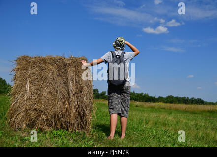 Jugendlich mit Rucksack steht von Stroh zu Stapeln Stockfoto