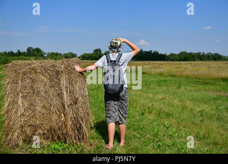 Jugendlich mit Rucksack steht von Stroh zu Stapeln Stockfoto