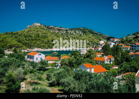 Gemütliche Stadt, entspannen, Sommer Feeling. Roten Dächer von Assos Dorf im üppigen Grün der mediterranen Ort der Insel Kefalonia Stockfoto