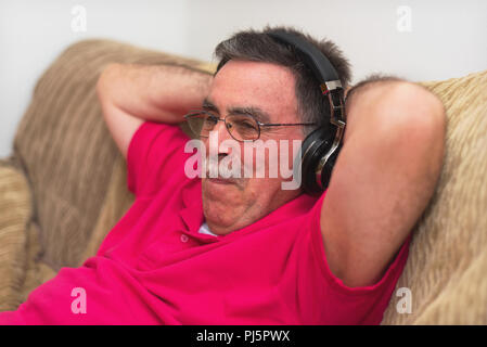 Entspannt älterer Mann im Kopfhörer zu Hause Musik hören Stockfoto