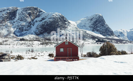 Schneebedeckte Berge mit Hütte über einen zugefrorenen See in Folkestad Norwegen Stockfoto