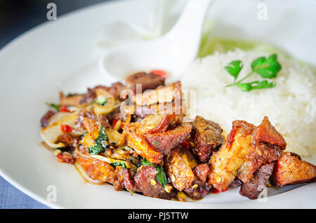 Wokgemüse knuspriges Schweinefleisch mit Thai Basilikum und Chili Sauce serviert mit gedämpftem Reis Stockfoto