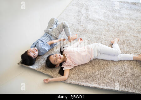 Süße Kinder liegen auf Teppich im neuen Haus Stockfoto