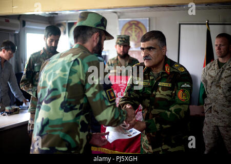 Der Provinz Helmand, Afghanistan (26. August 2018) - Afghanische Brig. Gen. Abdul Hadi, Afghan National Army (ANA) 215 Corps stellvertretender Kommandant, Hände ein ANA Soldat seine Abschlusszertifikat während einer Zeremonie für ein Train-the-trainer-Kurs an der regionalen militärischen Training Center auf Lager Shorabak. Die fast einmonatigen Kurs vermittelt Dozenten die Grundlagen der Krieger, damit Sie können, die wiederum die kommenden Klassen der neuen ANA territorialen Kraft, die in die sichere und sichere Wahlen zu den Leuten von Helmand und Provinzen in diesem Oktober unterstützen wird, unterrichten. (U.S. Marine Corps Foto Stockfoto