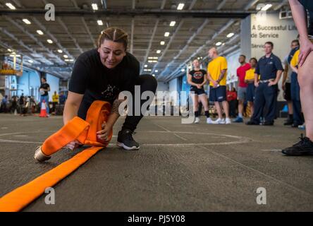 180827-N-ET 513-0115 ATLANTIK. (Aug. 27, 2018) Aviation Machinist Mate Airman Wendy PenaCervantes, von Las Vegas, Brötchen, ein firehose bei der Schadensbegrenzung Olympics im Hangar Bucht von dem Flugzeugträger USS George H.W. Bush (CVN 77). Das Schiff ist im Gange, die Durchführung von routinemäßigen Übungen Träger bereit zu halten. (U.S. Marine Foto von Mass Communication Specialist 3. Klasse Kallysta Castillo) Stockfoto