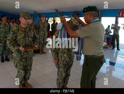 Brig. Gen. Falur Rate Laek, Stabschef der Timor-Leste Defence Force, präsentiert Lt.Cmdr. Paul Duenas, von Yona, Guam, an die in den Küstenzonen Riverine Group (CRG) 1 Det zugeordnet. Guam mit einem zeremoniellen Tais bei der Abschlussfeier von CARAT Timor-Leste 2018 bei Hera Naval Base, 12.08.30, 2018. CARAT Timor-Leste 2018 ist darauf ausgelegt, die Sicherheit des Seeverkehrs betrifft die gemeinsame Adresse, Beziehungen aufzubauen und die Interoperabilität zwischen den teilnehmenden Kräfte stärken. (U.S. Marine Foto von Mass Communication Specialist 3. Klasse Danny Ray Nuñez jr./Freigegeben) Stockfoto