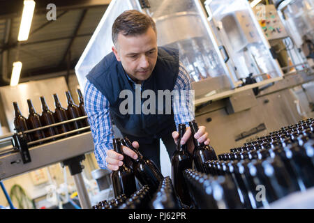Ein Arbeiter, der Fördertechnik mit Weinflaschen verschieben Stockfoto