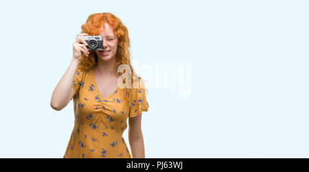 Junge rothaarige Frau fotografieren Holding vintage Kamera mit einem glücklichen Gesicht stehen und lächelnd mit einem selbstbewussten lächeln zähne Stockfoto