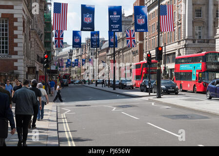 Viel befahrenen Straße Szene in Piccadilly, London. Werbebanner für die NFL und die Britische und Amerikanische Flaggen hängen über der Straße. England, Großbritannien Stockfoto