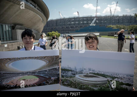 Tokio, Japan. 05 Sep, 2018. 05.09.2018, Tokyo, Japan: Helfer anzeigen Zeigt mit einer Simulation der neuen Bau des Olympiastadions für die Olympischen Sommerspiele 2020 in Tokio vor dem Stadion Baustelle. Fast zwei Jahre vor der nächsten Spiele, die Veranstalter präsentierten den Stand der Vorbereitungen für die Übereinstimmungen mit der internationalen Medien. Die ultra-modernen Tokyo Bay Zone wird der Mittelpunkt der Sommerspiele. Medaillen werden in 33 Sportarten vergeben, plus Baseball/Softball, Karate, Skateboard, Sport Klettern und Surfen. Quelle: Michael Kappeler/dpa/Alamy leben Nachrichten Stockfoto