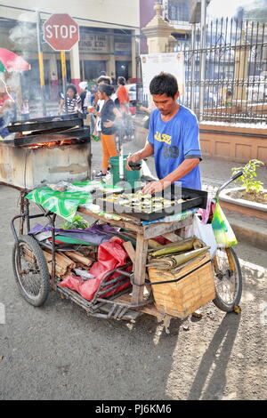 Cebu, Philippines-October 18, 2016: streetfood Verkäufer Köche und verkauft Philippinischen Köstlichkeiten aus ihrer Nahrung Fahrrad - Warenkorb angeheizt durch Brennholz in stationiert Stockfoto