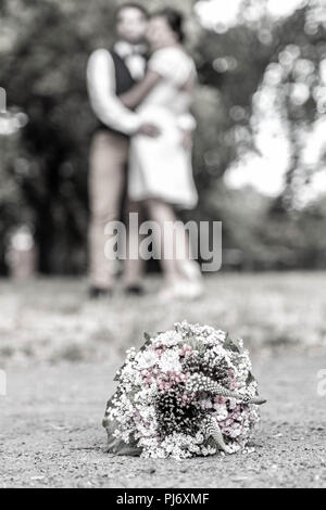 Wedding Bouquet vor der Jungvermählten paar Hintergrund, Küssen geringer Tiefe. Stockfoto