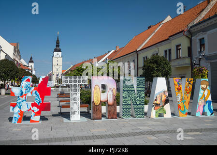 TRNAVA, SLOWAKEI - 29. AUGUST 2018: Fußgängerzone mit original hashtag Art Renaissance Stadt Turm und Kirche der Heiligen Dreifaltigkeit im Hintergrund. Stockfoto