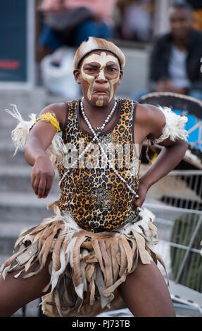 Mann in Tribal afrikanische Kleidung unterhaltsam Touristen auf den Straßen von Kapstadt, Südafrika Stockfoto