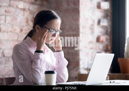 Junge müde Frau in Brillen im Büro arbeiten Stockfoto