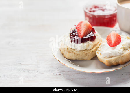 Cream Tea mit Scones und Clotted Cream, Himbeermarmelade, Erdbeeren auf dem weißen Tabelle, kopieren Platz für Text, selektiver Fokus Stockfoto