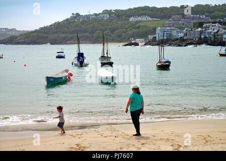 Das Meer und der Hafen von St. Ives in Cornwall an einem Sommertag mit einer Mutter und Kleinkind spielen am Strand, England Großbritannien Stockfoto