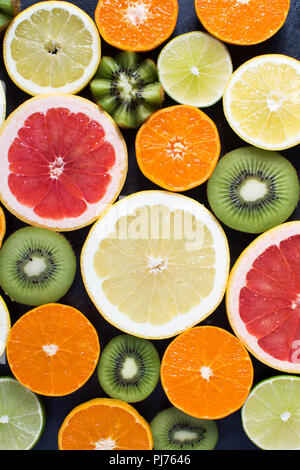 Zitrusfrüchte: Orangen, Zitronen, Grapefruits und Zitronen und Kiwis auf der schwarzen Schiefer Hintergrund, Ansicht von oben Stockfoto