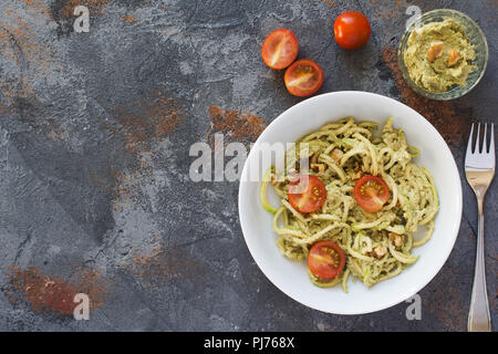 Spiralized Zucchini Spaghetti mit Avocado und Walnuss Pesto und Tomaten, am grauen Stein Tabelle, selektiver Fokus, Ansicht von oben, kopieren Platz für Text Stockfoto