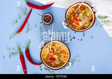 Suppe mit kleinen Nudeln, Gemüse und Fleisch in Schale auf der blauen Tabelle. Italienisches Essen. Ansicht von oben. Flach Stockfoto