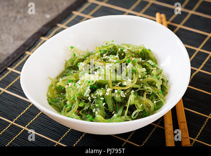 Wakame Chuka oder algensalat mit Sesam in der Schüssel auf schwarzem Hintergrund. Traditionelle japanische Speisen. Stockfoto