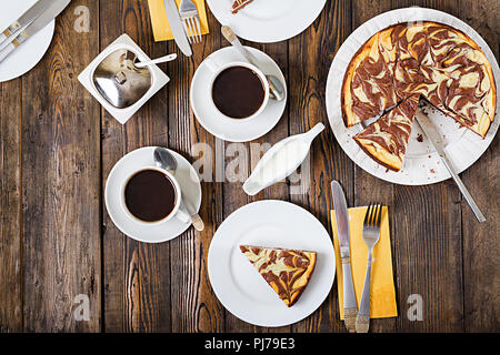 Schokolade Käsekuchen und Kaffee auf Holz- Hintergrund. Tasse Kaffee und Käsekuchen. Ansicht von Oben. Flach Stockfoto