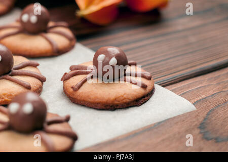 Lustig lecker Ingwer Kekse für Halloween auf dem Tisch. Satz von Schokolade Halloween spinne Cookies auf Papier für Backen und Holz- Hintergrund Stockfoto